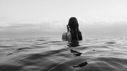 Rear view of woman in sea against sky