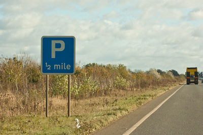 Information sign by road against sky