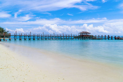 Pier on sea against cloudy sky