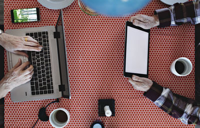 Directly above view of retired couple using technologies at dining table