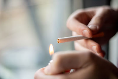 Close-up of hand holding lit cigarette