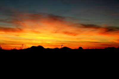 Scenic view of silhouette landscape against orange sky