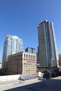 Low angle view of modern buildings against clear blue sky