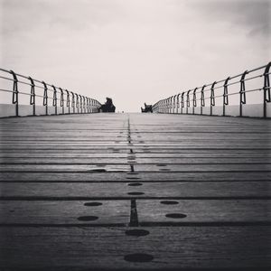 Surface level of footbridge over pier against sky