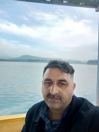 Portrait of young man against lake against sky