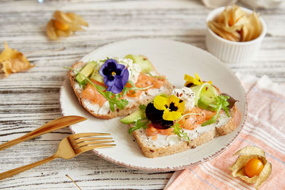 Healthy appetizer breakfast with cottage cheese, smoked salmon, arugula, avocado, edible flowers