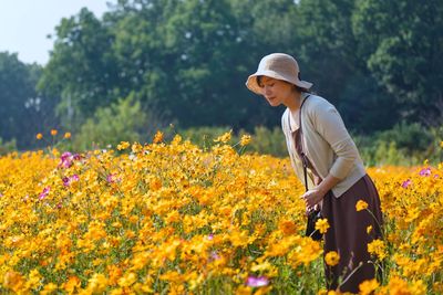 Side view of young woman with flowers on field