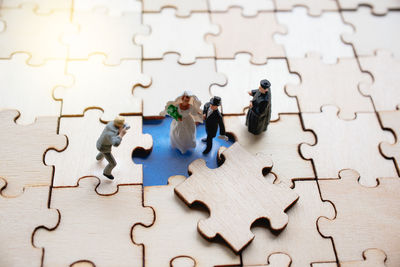 High angle view of figurines on wooden jigsaw puzzle