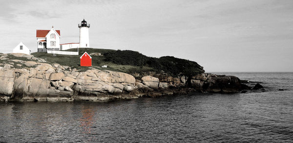 Lighthouse by sea against sky