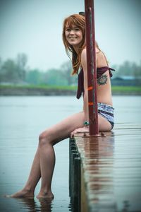 Woman sitting on pier over lake