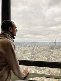 Rear view of man looking at urban view against sky