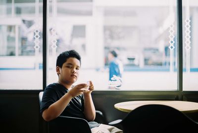 Portrait of boy sitting at table in restaurant