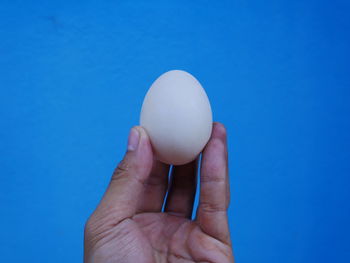 Close-up of hand holding ice cream over blue background