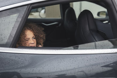 Girl looking through window of car