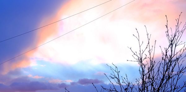 Low angle view of power lines against cloudy sky