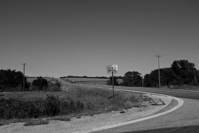 Road amidst field against clear sky