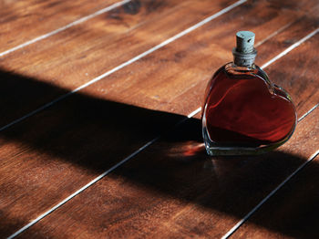 High angle view of red liquid in heart shape bottle on hardwood floor