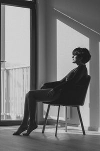 Side view of woman sitting on chair at home