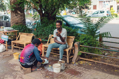 People sitting on bench against plants