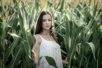 Portrait of young woman standing amidst plants