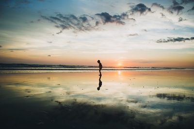 Silhouette man standing on beach against sky during sunset