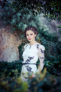 Portrait of young woman standing against tree