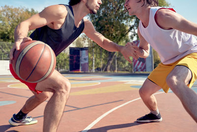 Midsection of players playing on basketball court