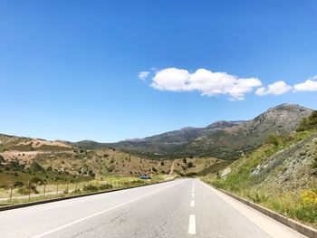 Road amidst mountains against blue sky