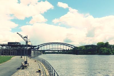 Bridge over river against cloudy sky