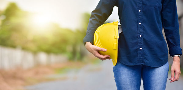 Midsection of man holding yellow while standing outdoors