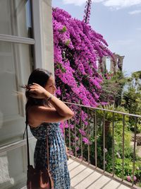 Woman standing by pink flowering plants