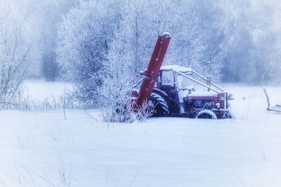 Snow on field by road against sky during winter