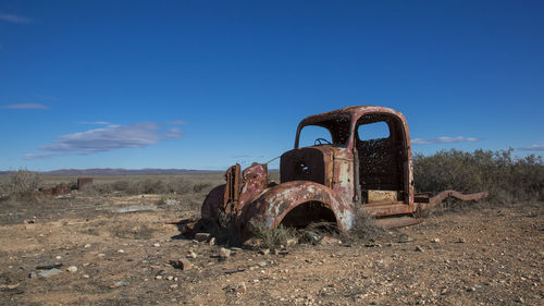 Abandoned truck on field against clear sky