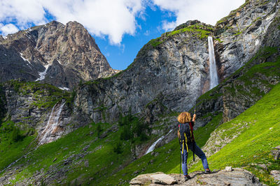 Rear view of person on rock against sky