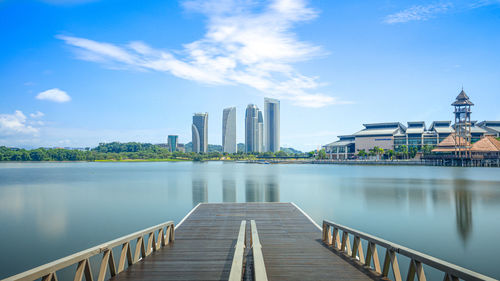 Bridge over river by buildings against sky