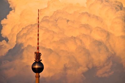 Low angle view of communications tower against cloudy sky