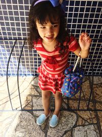 High angle view of cute girl standing by metal fence