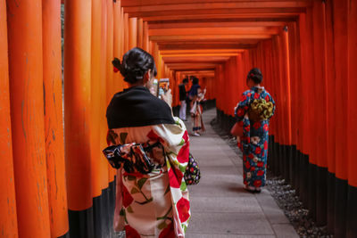 Rear view of friends standing against orange wall