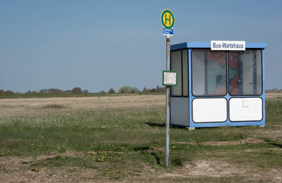 Information sign on field against sky