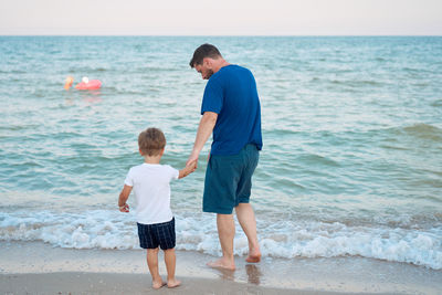 Full length of father and son standing at seashore