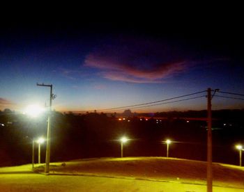 Illuminated street light against sky at night