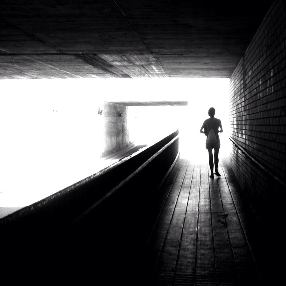 full length, the way forward, tunnel, walking, rear view, lifestyles, men, silhouette, architecture, built structure, indoors, standing, leisure activity, wall - building feature, diminishing perspective, light at the end of the tunnel, wall, vanishing point