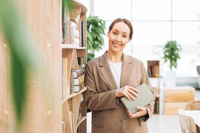 Adult smiling woman forty years with long hair in stylish beige suit and jeans at public place