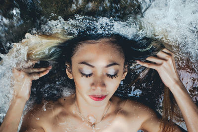 High angle view of beautiful naked woman in sea with eyes closed