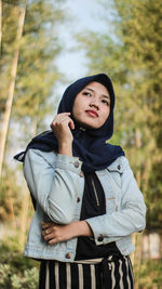 Thoughtful woman wearing hijab standing in park