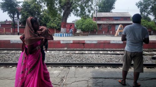 Rear view of people standing on railroad track