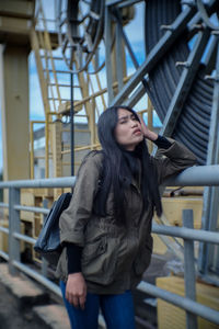 Portrait of woman standing against built structure in city