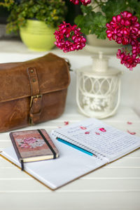 Diaries and bag below flowers at table
