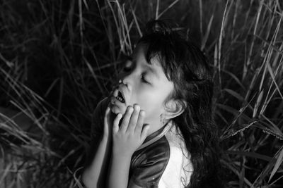 High angle view of girl with eyes closed by grass on field