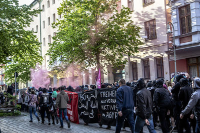 Crowd walking on street by buildings at may day